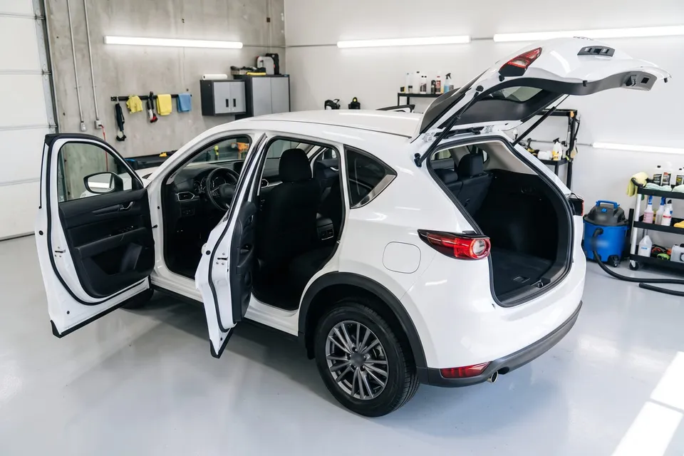 White SUV in a detailing bay with the doors and liftgate open after an interior and exterior detail