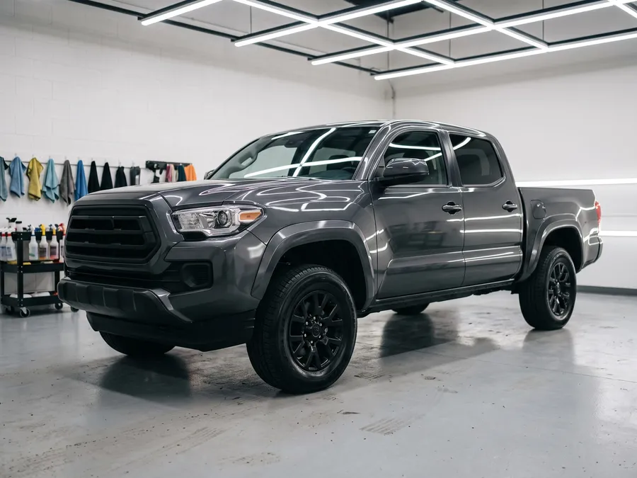 Freshly detailed dark gray pickup truck with glossy paint parked in a bright detailing shop bay