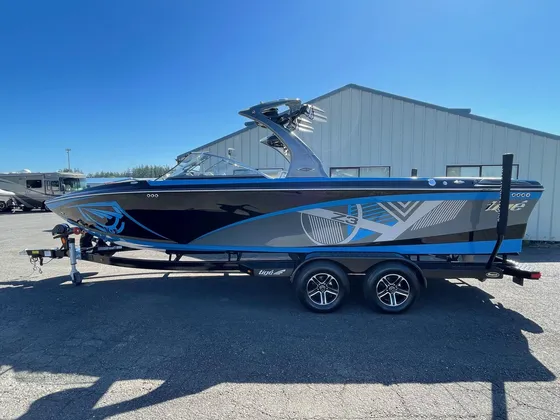 Black, blue and gray Tige Z3 wake boat with a tower on its trailer outside the shop in full sun