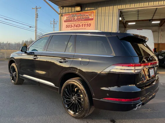 Black Lincoln Aviator with black wheels parked in front of the shop, seen from the rear driver side