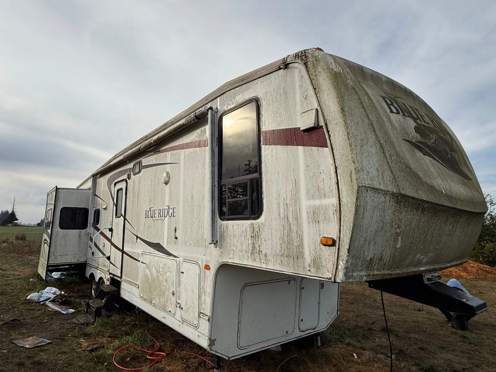 Blue Ridge fifth wheel sitting in a field with green mildew streaks across the front cap and walls