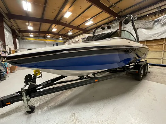 Blue, white and black ski boat with a tower sitting on a black trailer in the shop