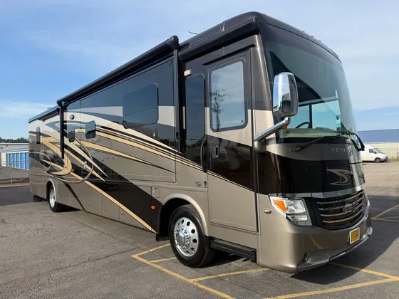 Brown and black Newmar Ventana diesel pusher motorhome parked on the lot in the sun