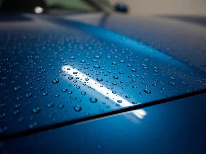 Water beading up on the ceramic coated hood of a dark blue car