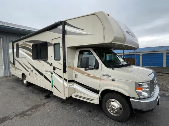 Tan Coachmen Leprechaun Class C motorhome on a Ford E-450 chassis, front passenger side