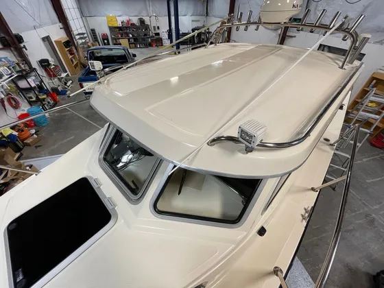 Cream cabin boat seen from the bow with stainless rails, rod holders and radar dome over the cabin roof