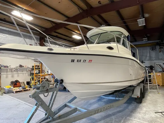 Cream walkaround cabin boat with stainless rails on an EZ Loader trailer inside the shop