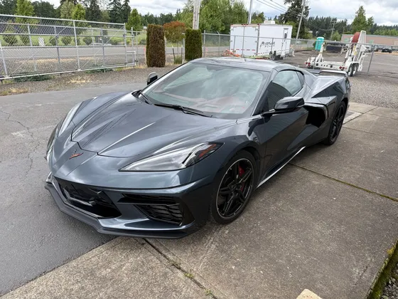Dark gray Corvette C8 with black wheels and red calipers parked on the concrete outside the shop