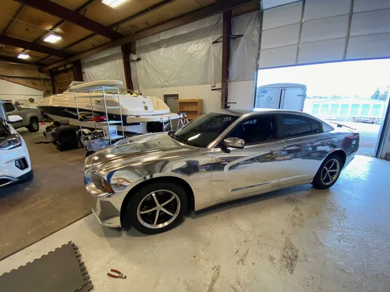 Dodge Charger covered in a chrome silver wrap inside the shop
