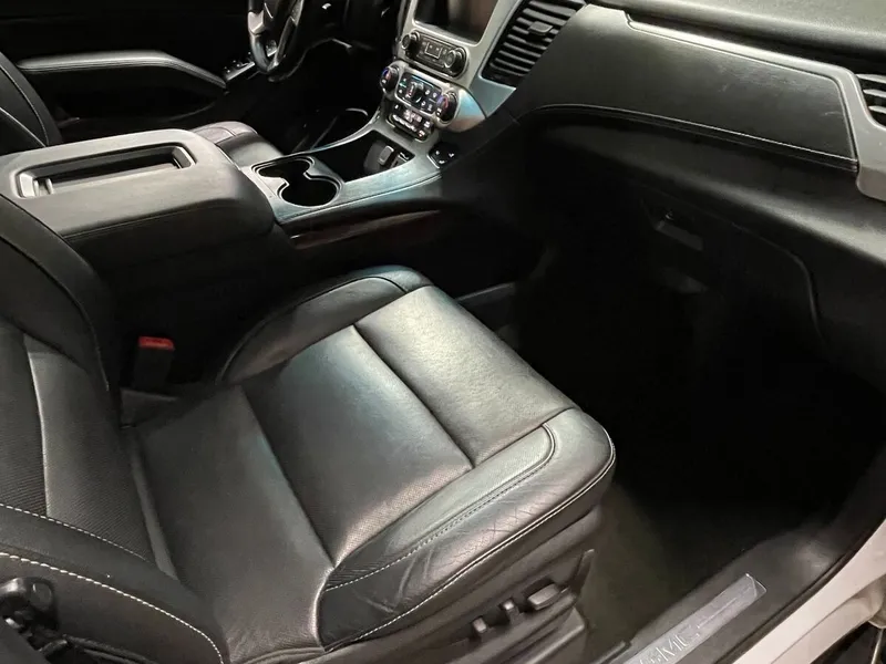 Black leather front passenger seat and dash of a GMC SUV seen through the open door in the shop