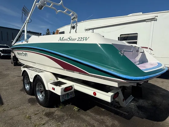 Green and cream MariStar 225V boat with blue tape along the hull edge, parked outside on its trailer