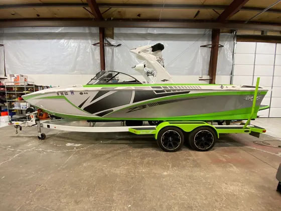 Green, white and gray wake boat with a Z3 badge and tower sitting on its trailer in the shop