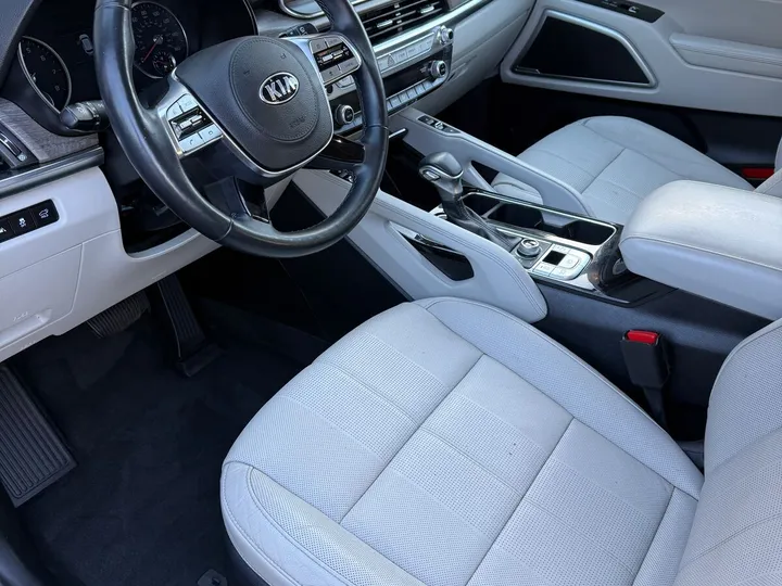 Front interior of a Kia Telluride with light gray leather seats and a black steering wheel