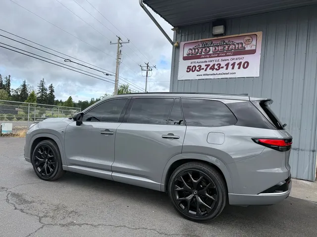 Light gray Lexus three-row SUV with black wheels parked beside the shop building