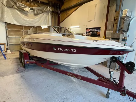 Maroon and cream bowrider on a matching maroon trailer inside the shop, starboard bow