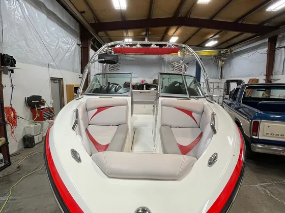 Front of a white and red MasterCraft ski boat with gray bow seats and a wake tower inside the shop