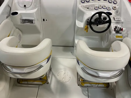 White performance boat cockpit with two bucket seats, gauges and steering wheel seen from behind