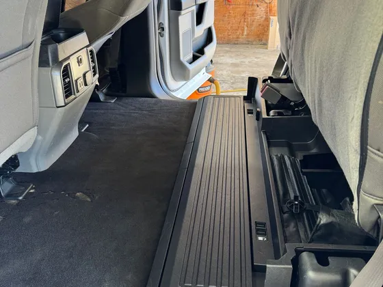 Clean dark carpet and fold-up storage panel in the back seat area of a crew cab pickup