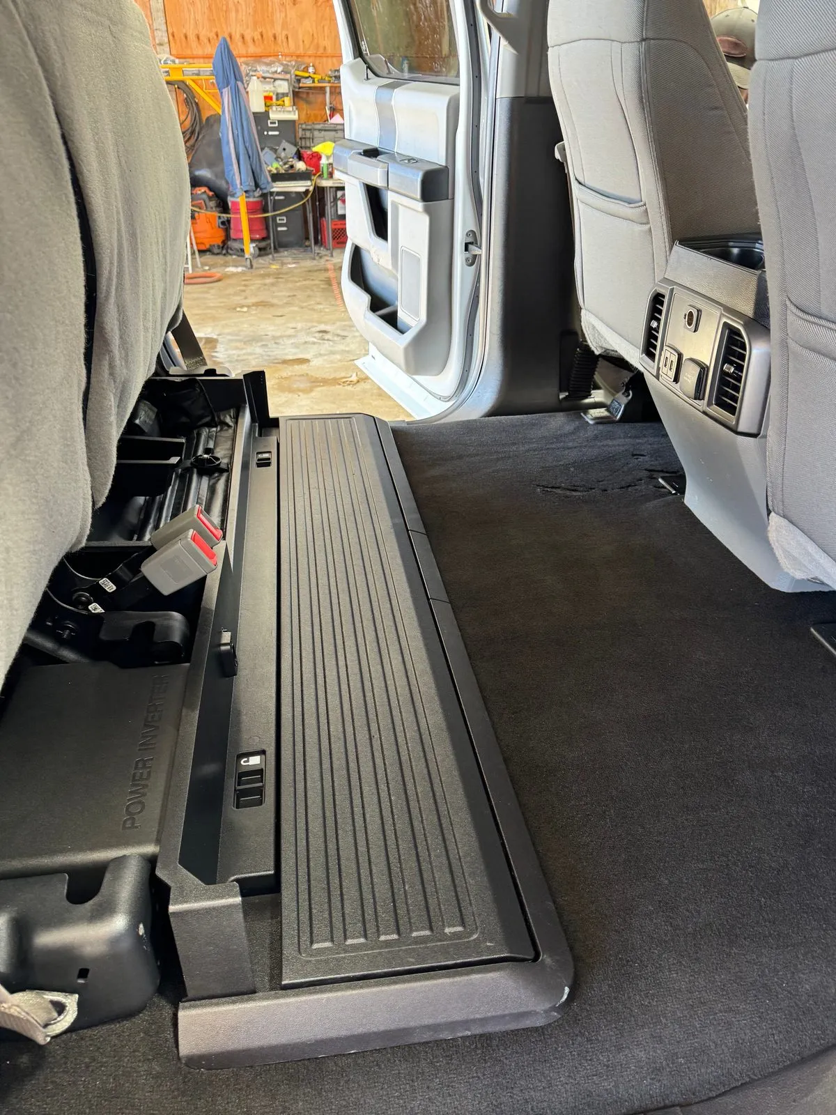 The same crew cab back seat area with clean dark carpet and the fold-up storage panel
