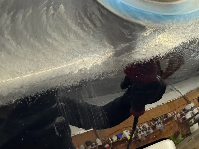 Orbital polisher with a blue pad working compound across a black hood