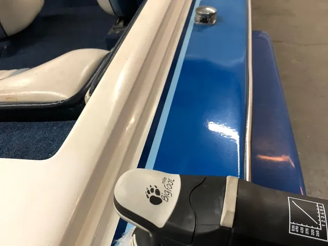 Dual-action polisher with a blue pad working along the blue side of a boat, shine on the finished strip