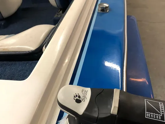 Dual-action polisher with a blue pad working along the blue side of a boat, shine on the finished strip