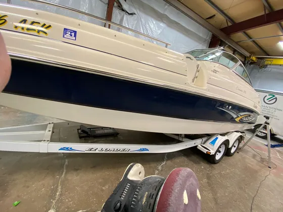 Cream and navy Rinker cabin boat on a trailer with a polisher and sanding-style pad on the floor in front