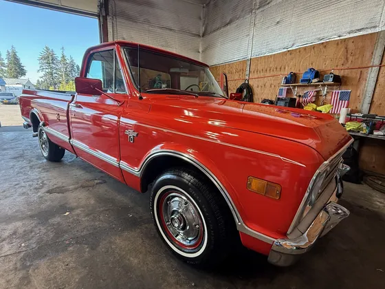 Red late 1960s Chevrolet C10 pickup with whitewall tires and chrome bumper parked in the shop bay