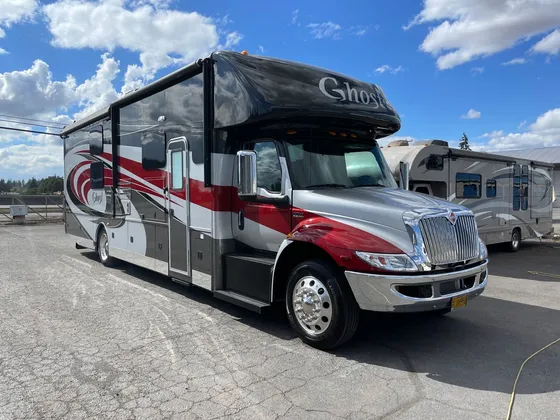 Red, silver and black Super C motorhome with chrome wheels parked in the lot