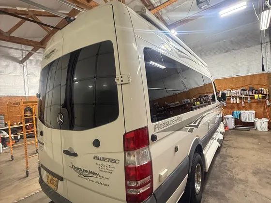Cream Sprinter camper van, clean, parked in the shop bay seen from the rear driver side
