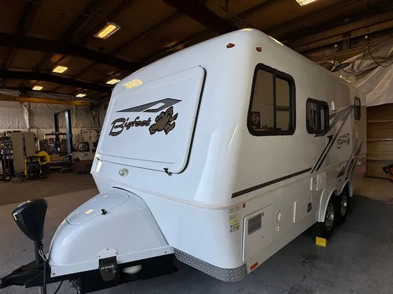 White Bigfoot fiberglass travel trailer parked inside the shop bay