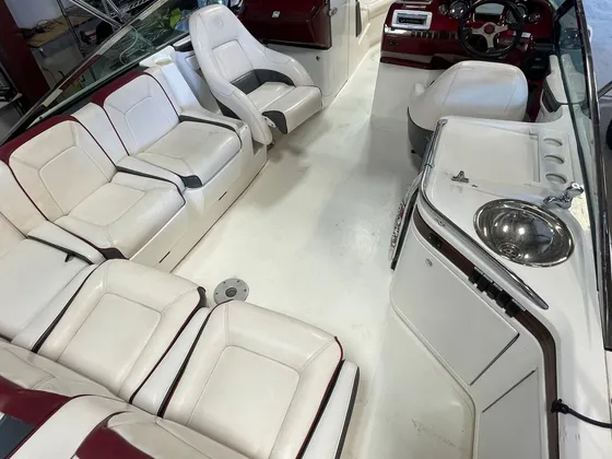 Cockpit of a bowrider with white and burgundy seats, a wet bar sink and a burgundy dash