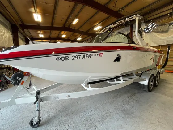 White and red Centurion wake boat with a tower on a white trailer inside the shop