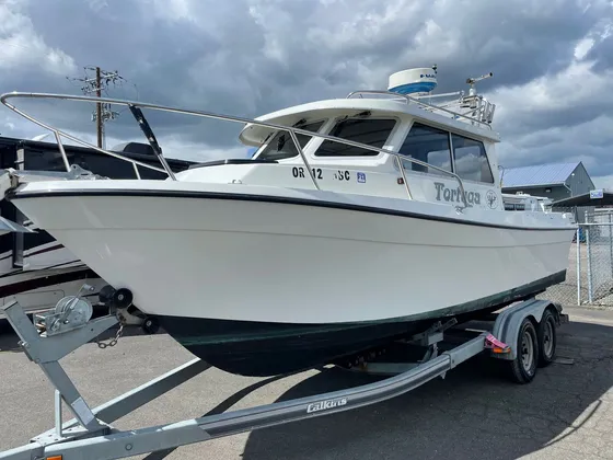 White cabin boat with a radar dome on a Calkins trailer in a paved lot, bow and port side