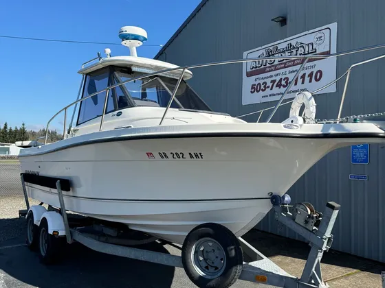 White Trophy fishing boat with a radar dome on a trailer next to the shop building